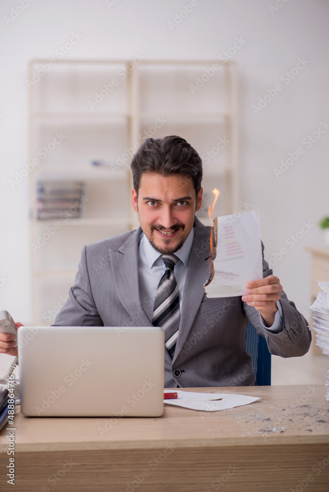 Young male employee unhappy with excessive work in the office Young male employee unhappy with excessive work in the office