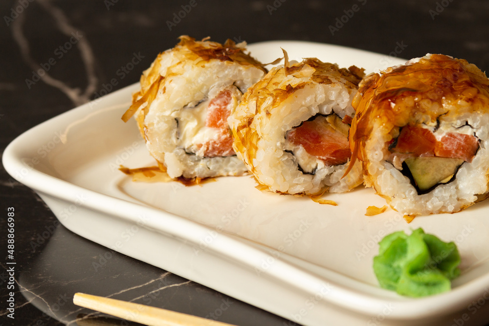 sushi rolls of different varieties lie on a white tray on a dark background. sushi rolls of different varieties lie on a white tray on a dark background.