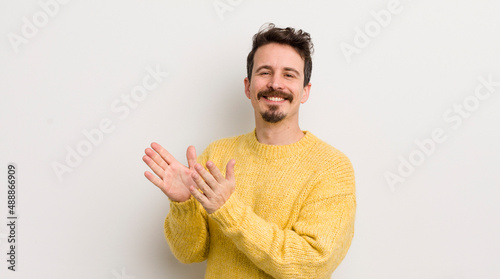 hispanic young man feeling happy and successful, smiling and clapping hands, saying congratulations with an applause