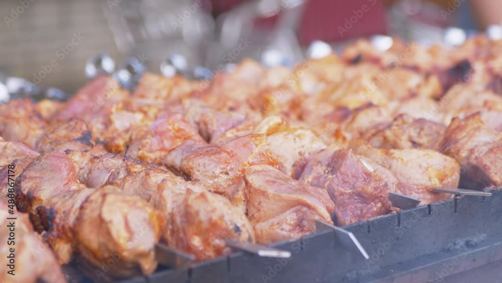 Juicy Pork Kebabs are Fried on an Open Grill in Smoke and Soot. Preparing fried pieces of meat on skewers, on hot coals, baked on the grill. Street fast food trade, sale in the market. Food court.