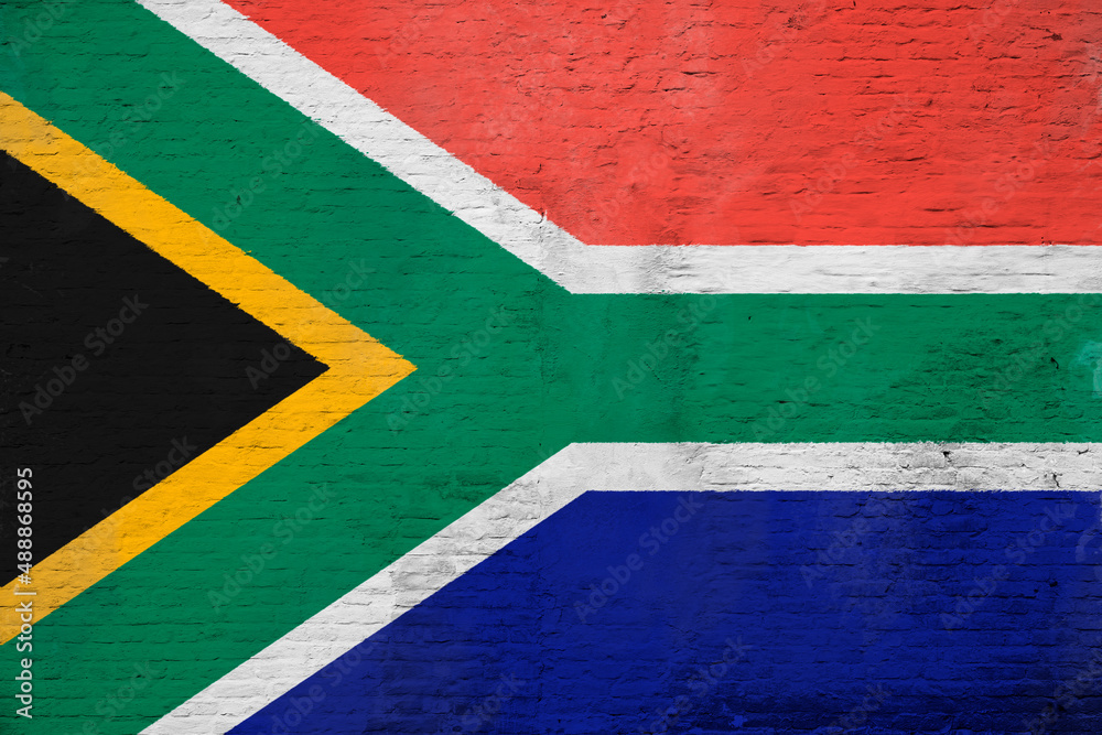 Full frame photo of a weathered flag of South Africa painted on a plastered brick wall.