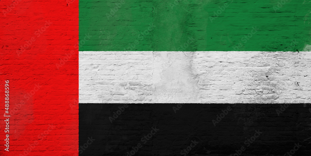 Full frame photo of a weathered flag of United Arab Emirates (UAE) painted on a plastered brick wall.