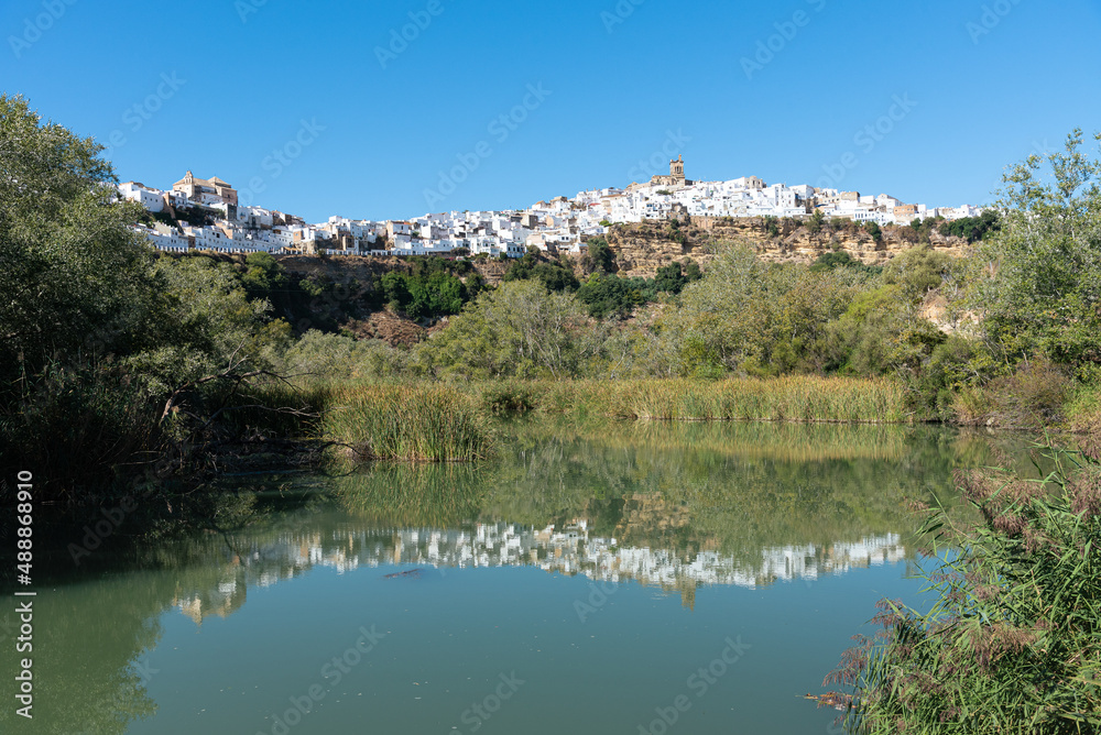 City landscape at daylight of the beautiful andalusian white town of Arcos de la Frontera reflected in the water of Guadalete river, Cadiz, Andalusia, Spain
