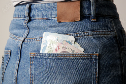 Woman holding Turkish lira banknotes in pocket of her jeans