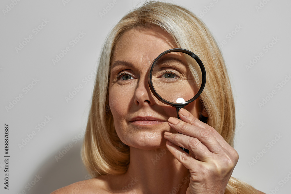 Mature woman looking away through magnifying glass Mature woman looking away through magnifying glass
