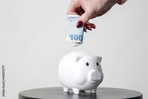 Hand is putting Turkish lira into piggy bank   photo