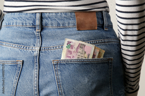 Woman holding Qatar riyal banknotes in pocket of her jeans