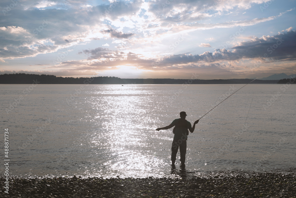 Man in silhouette casting a fly fishing pole line out over sunset lake. Man in silhouette casting a fly fishing pole line out over sunset lake.