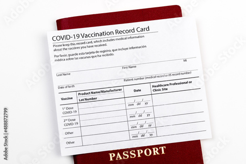 Coronavirus vaccination record card, biometric passport and blue medical mask on light gray desk. Concept of defeating Covid-19. Vaccination as prerequisite for travel - Image