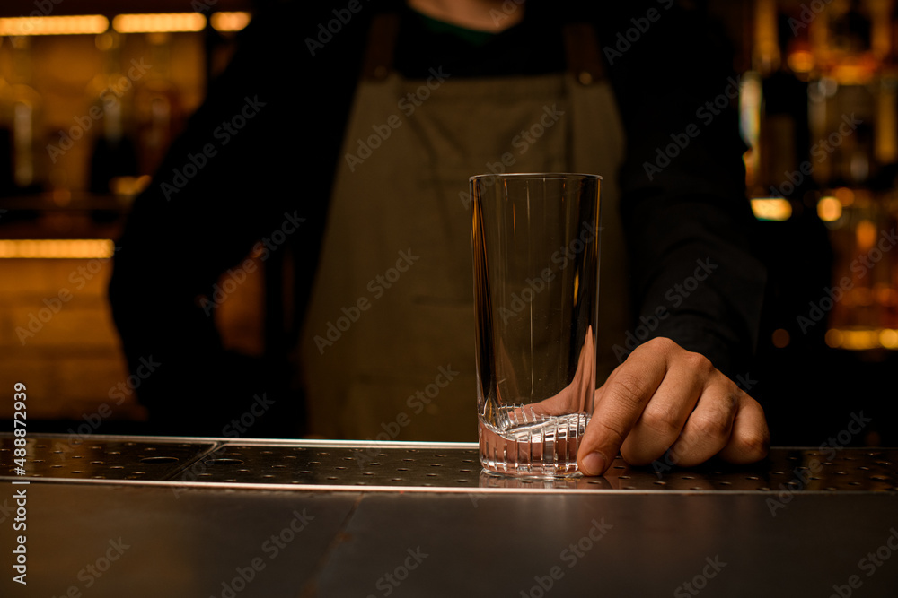 front view of clean transparent empty cocktail glass on bar counter which male hand holds