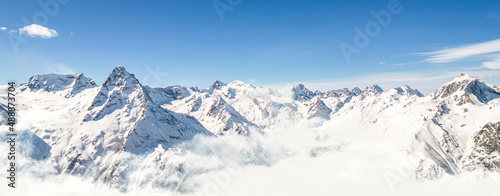 Panorama of mountains above the clouds under a clear sky on a sunny day 