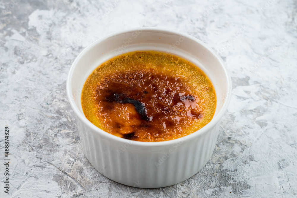 Single bowl of creme brulee. Burned cream with caramelized brown sugar in a ramekin bowl Single bowl of creme brulee. Burned cream with caramelized brown sugar in a ramekin bowl