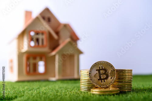 Pile of bitcoin coins in front of house