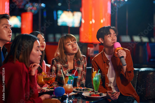Group of young asian people enjoying at karaoke nightclub