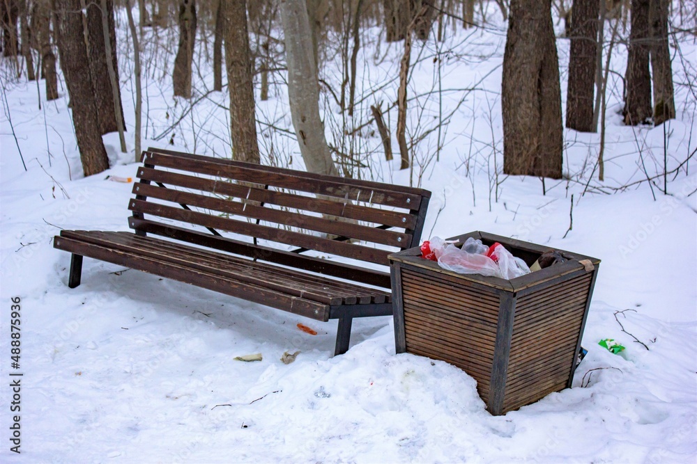 Garbage near the bench in winter. Bench in winter and slop with garbage and waste.