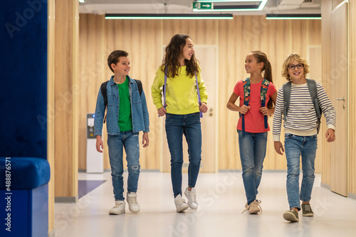Schoolchildren with backpacks walking in corridor © zinkevych