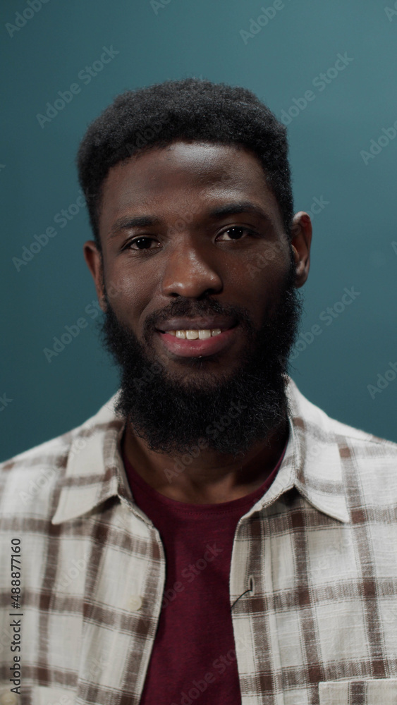 Fototapeta premium Carefree stylish dark-skinned young guy posing in checkered shirt isolated in a green studio