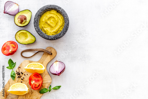 Homemade guacamole avocado dip in mortar with ingredients