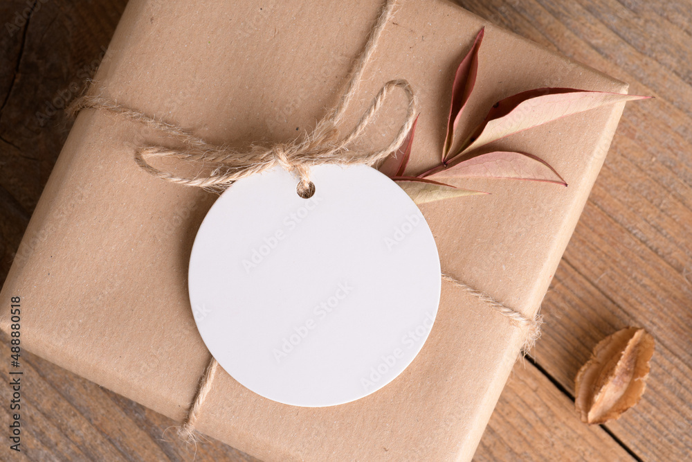 Φωτογραφία Round white gift tag mockup on craft wrapped presents on rustic wooden backgroun