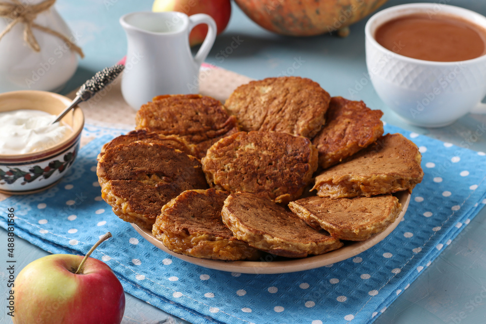 Homemade pancakes with pumpkin and apples for breakfast, as well as a cup of coffee with milk on a light blue background Homemade pancakes with pumpkin and apples for breakfast, as well as a cup of coffee with milk on a light blue background