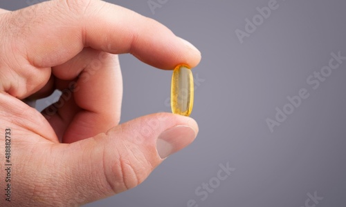 A hand holding a medical capsule pill between fingers