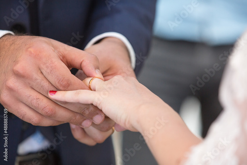 Close-up bride and groom putting engagement ring on finger