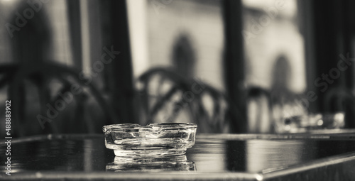 Terrace of a cafe with empty glass ashtray on a table. Paris, France. Smoking addiction health issue. Black white historic photo.