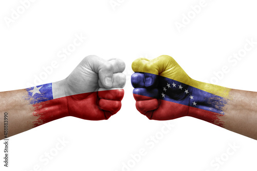 Two hands punch to each others on white background. Country flags painted fists, conflict crisis concept between chile and venezuela