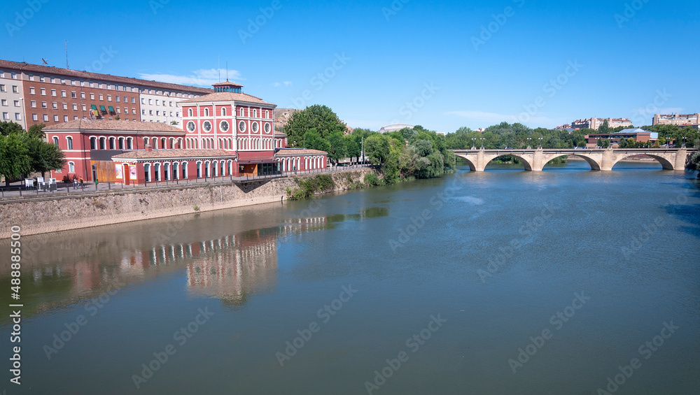 cityscape of the river next to the library building of la rioja in logroño spain, a bridge can be seen in the background.