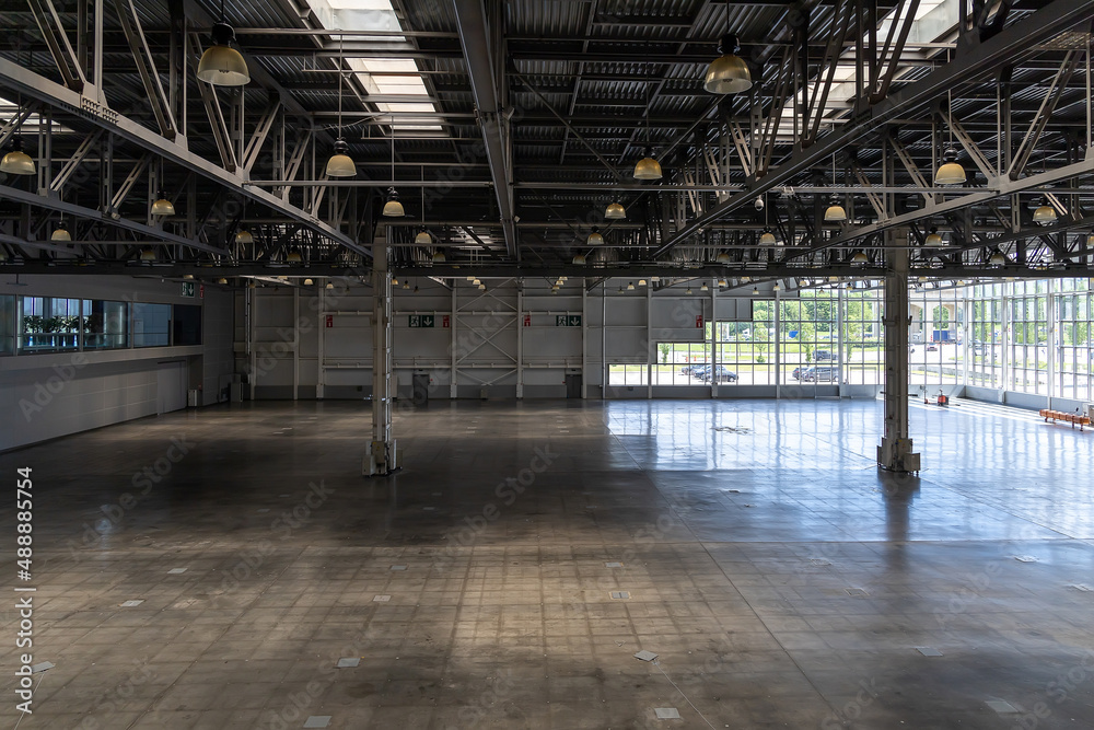 Spacious empty pavilion with windows for exhibitions and fairs. Hangar, a place intended for storage of large-sized objects. Modern large warehouse or storage