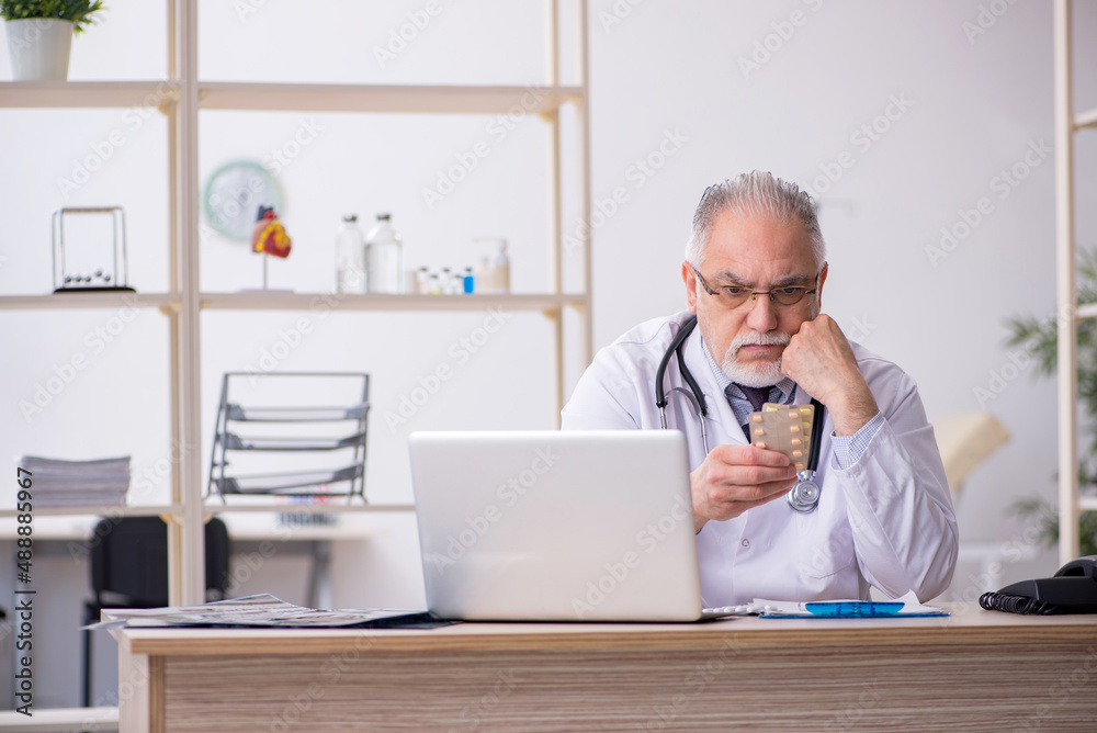 Old male doctor working in the clinic Old male doctor working in the clinic