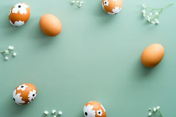 Happy Easter flat lay composition. Easter eggs with flowers on pastel green background. Easter card design, template.