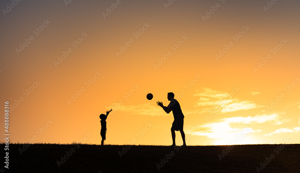 Silhouette of father and his child playing sports activity throwing ball in the park 