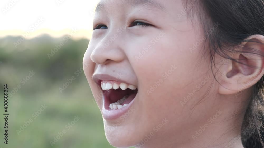 Portrait happy Asian little child girl smiling, laughing, looking at camera with beautiful sunset or sunrise in summer or spring nature outdoor background. Concept of portrait, happy children, family. Portrait happy Asian little child girl smiling, laughing, looking at camera with beautiful sunset or sunrise in summer or spring nature outdoor background. Concept of portrait, happy children, family.