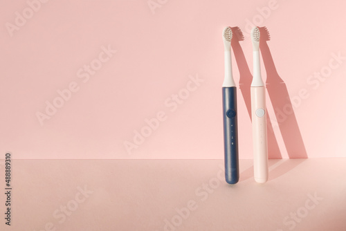 Two new modern ultrasonic toothbrushes. Dental care supplies on pink pastel background. Oral hygiene  dental and gum health  healthy teeth. Dental products Ultrasonic vibration toothbrush.