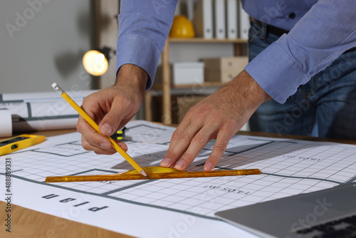 Architect working with construction drawings in office, closeup