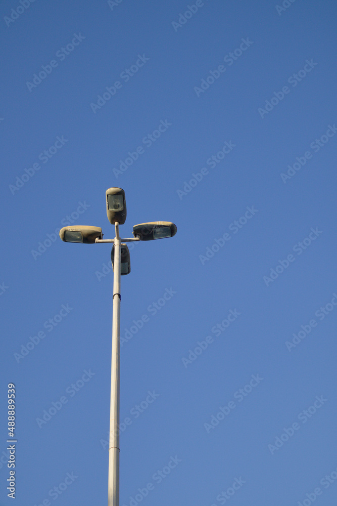 Image of a post with several lampposts on a blue sky