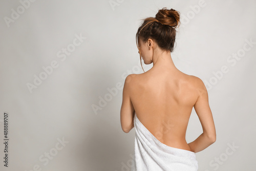 Back view of woman with perfect smooth skin on light grey background, space for text. Beauty and body care
