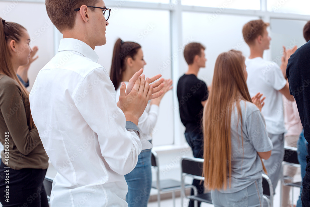 group of young people standing applauding in the conference room . group of young people standing applauding in the conference room .