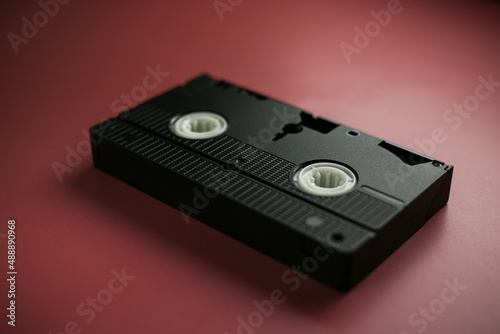 Close-up classic cassette tape on a red-burgundy background, outdated data storage
