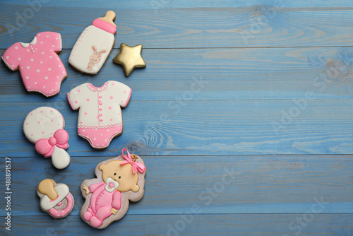 Cute tasty cookies of different shapes and space for text on light blue wooden table, flat lay. Baby shower party