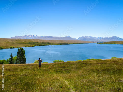 A female tourists stops to enjoy the scenic view towards the mountains above Lake Alexandrina, in Canterbury, New Zealand