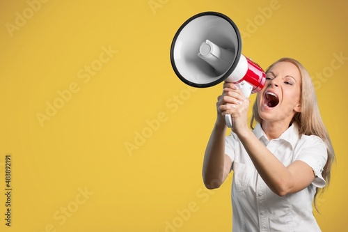 Excited beautiful woman talking seriously holding megaphone in hands