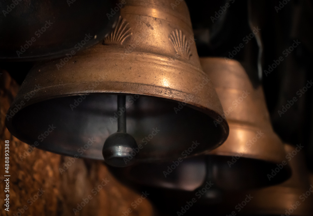 Cowbells hanging in a row, the middle one in focus. Stock Photo Adobe