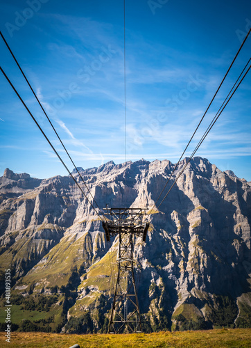 Symmetric view of a cable car mast staning on a mountain, with mountains in the background on the other side of the valley. Taken in Leukerbad