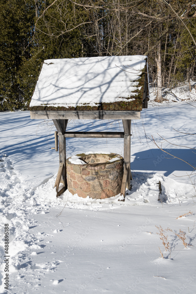 A rustic old fashion well is covered in snow in the cold winter.