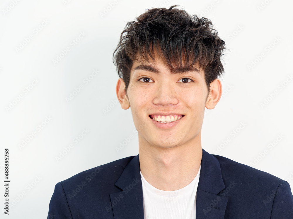 Portrait of handsome Chinese young man in dark blue leisure suit standing and posing against white wall background. Smiling and looking at camera confidently, front view. Portrait of handsome Chinese young man in dark blue leisure suit standing and posing against white wall background. Smiling and looking at camera confidently, front view.
