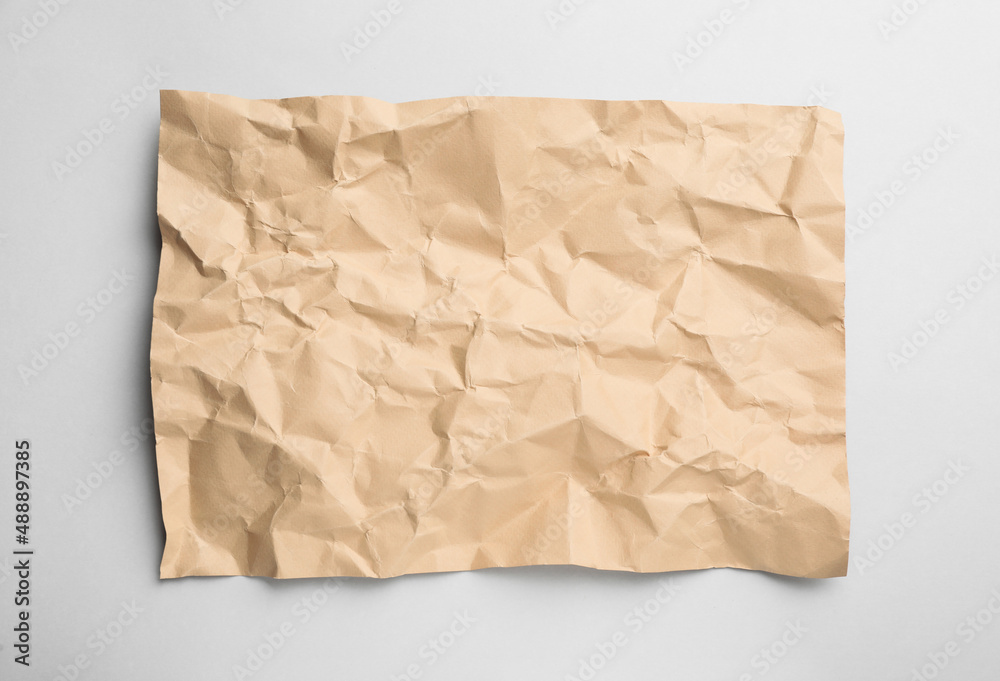 Sheet of crumpled brown paper on white background, top view