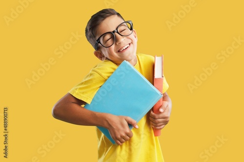 Happy school boy wearing glasses, holding backpack going to school, enjoying studying,