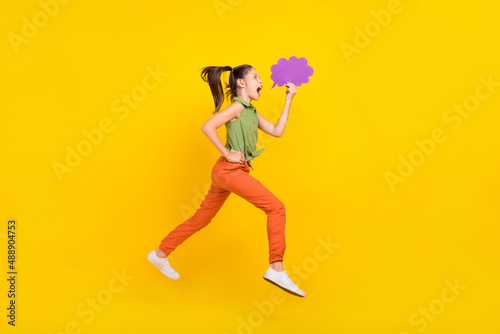 Photo of excited funny student girl wear green shirt smiling jumping high running fast mind cloud empty space isolated yellow color background
